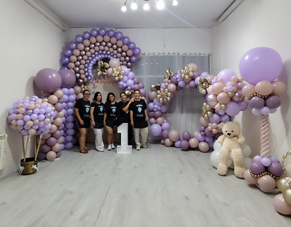 Alumnas de La Glover Class junto a un arco de globos lila para bautizo