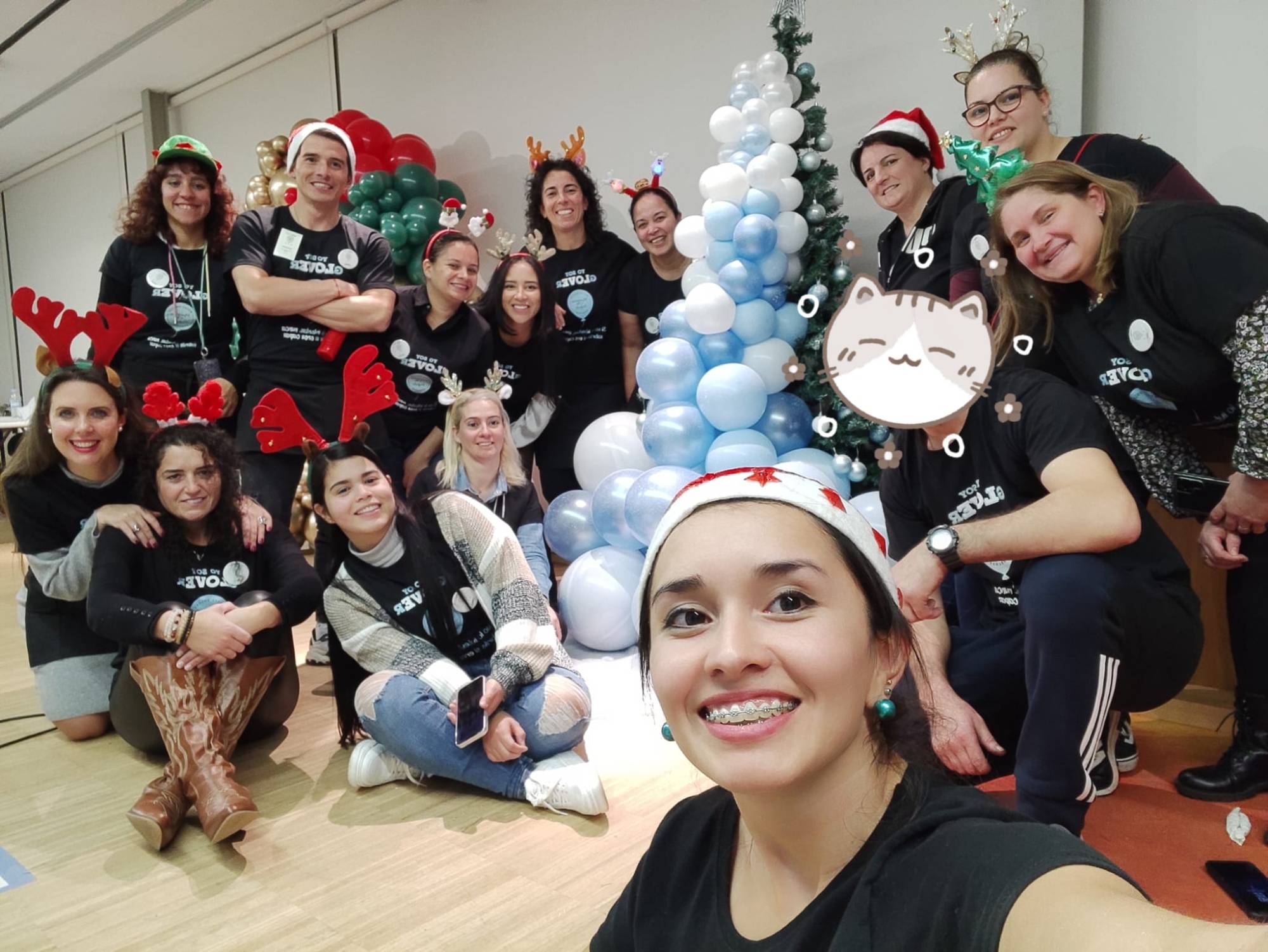 Alumnas de La Glover Class con gorros navideños junto a un árbol de globos