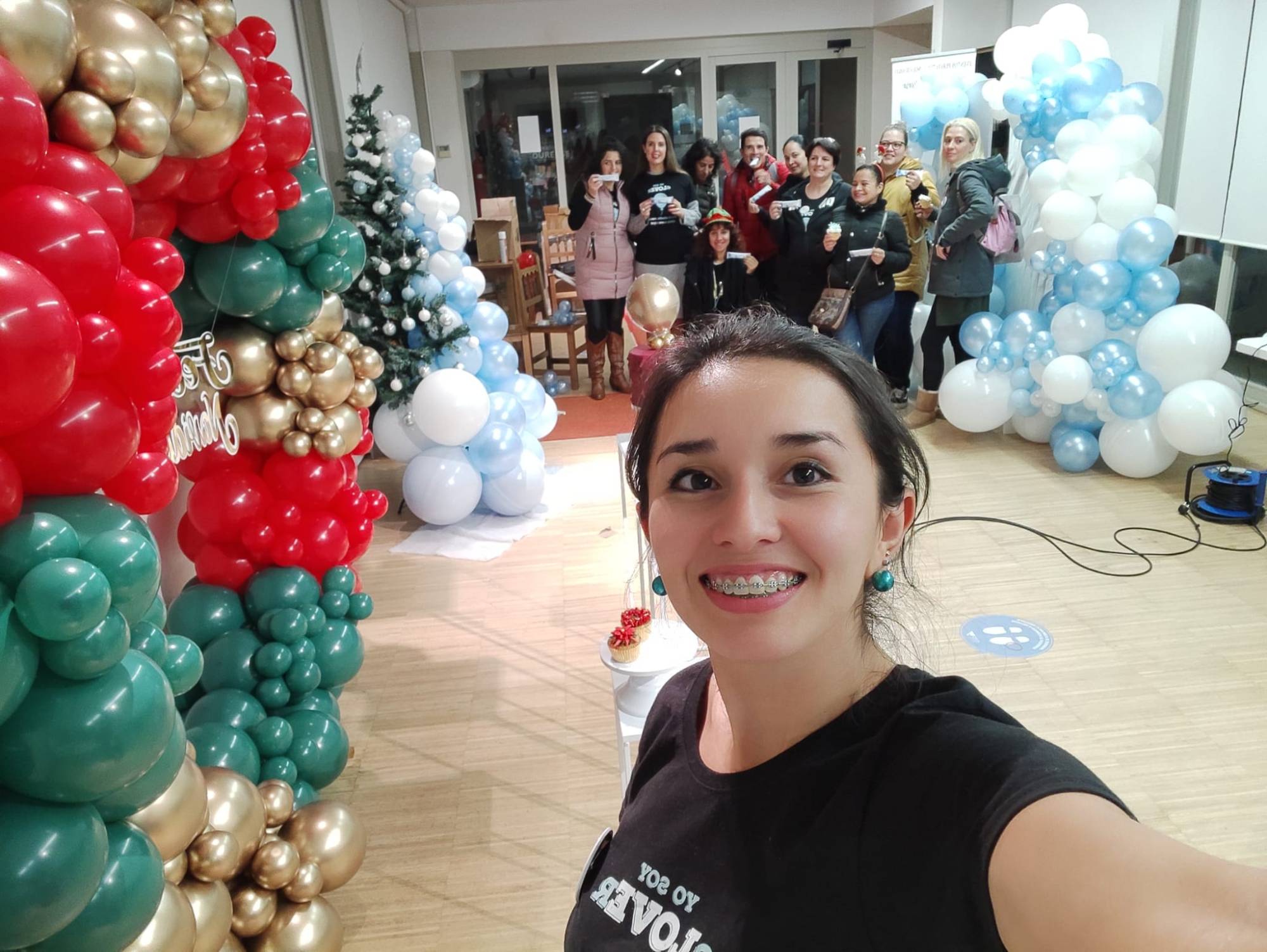 Carolina junto a columnas de globos navideñas y alumnas de fondo