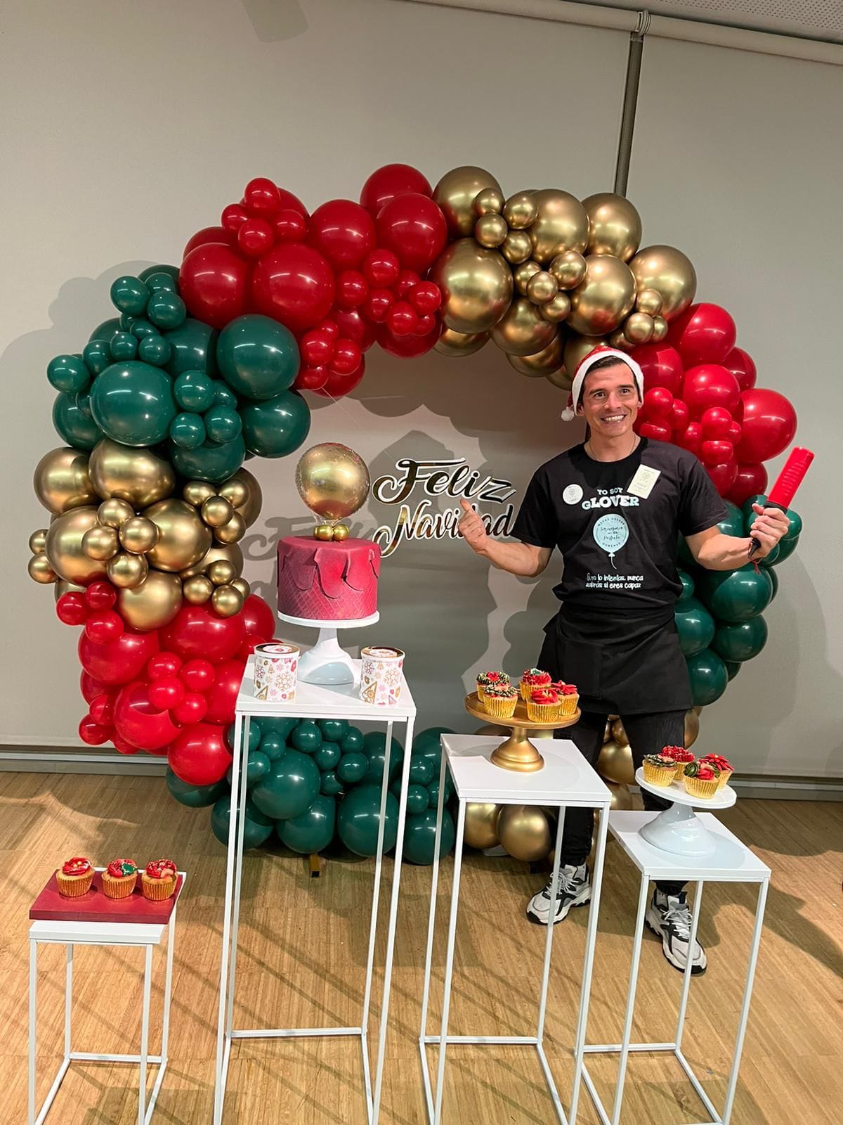 Arco navideño de globos rojo, verde y dorado con cartel Feliz Navidad