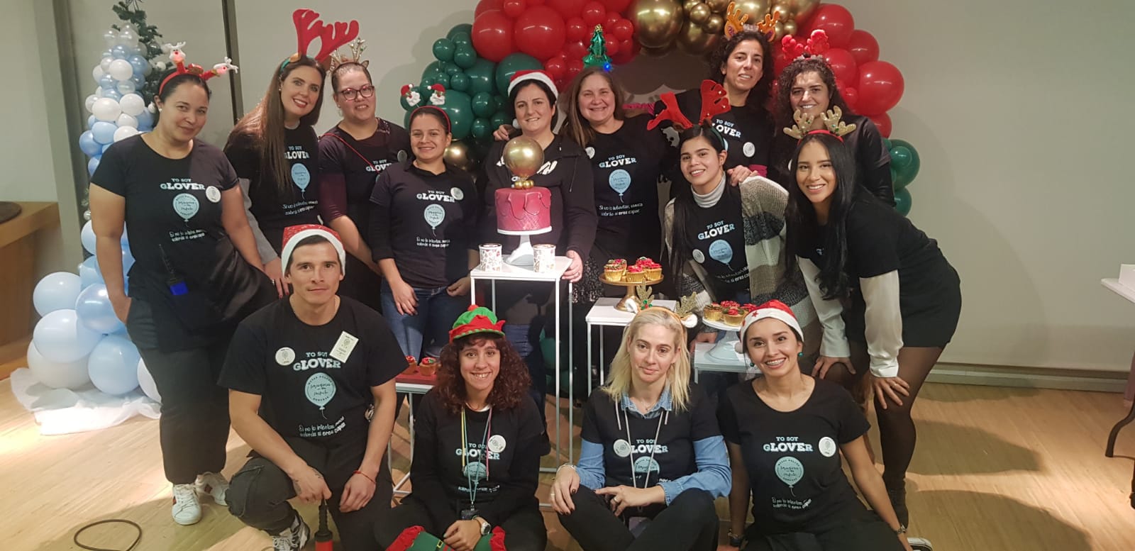 Grupo de Glovers con gorros navideños junto a un arco de globos